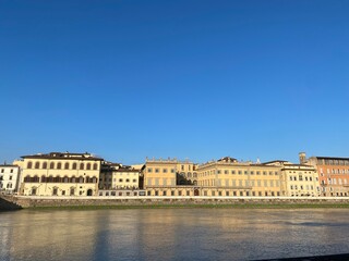 Golden buildings reflecting in blue Arno River, Florence