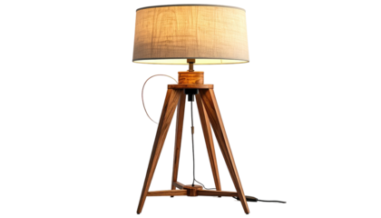 Illuminated lamp featuring a tan shade supported by a wooden tripod base, creating a warm, inviting glow