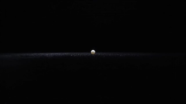 Camera dollies back to reveal a single, tiny pearl on a vast, black expanse.