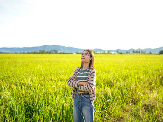 Woman stands confidently in lush green rice field, gazing thoughtfully at horizon. vibrant...
