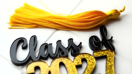 Graduation celebration with a gold and black 'Class of 2027' sign and tassel