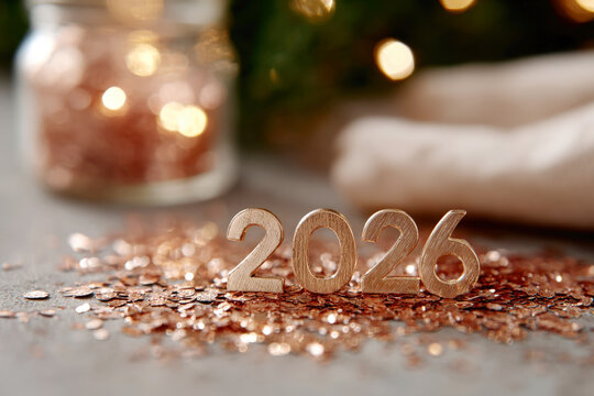 Golden Textured 2026 Numbers on Sparkling Rose Gold Confetti Surface with Bokeh Background