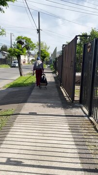 Hombre mayor caminando por la ciudad con carro de compras.