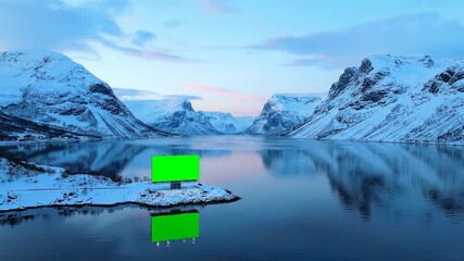 A futuristic green screen billboard stands on a snowy island in a serene winter landscape with snow-capped mountains reflecting in the calm water under a pastel sky