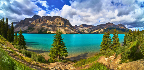 Obraz premium Panoramic View of Turquoise Bow Lake with Rocky Mountains and Evergreen Trees