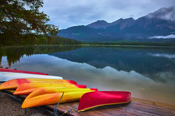 Colorful Canoes and Kayaks on Tranquil Lake with Mountain Reflections and Pine Trees
