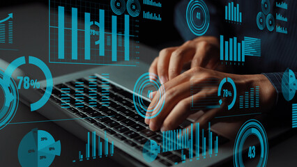 A close-up view of hands typing on a laptop with vibrant digital graphs and charts overlaying the scene, illustrating data analysis and modern technology concepts in a professional setting. Xenic