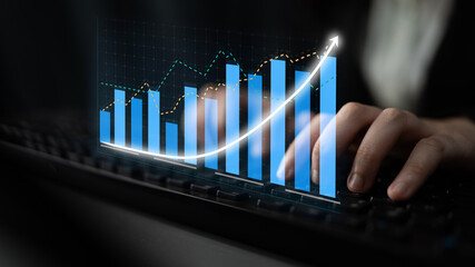A close-up view of hands typing on a keyboard with digital financial charts overlay, representing modern business growth and strategic analysis in finance. Impute