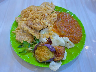 A complete set of Indonesian side dishes: crispy fried tofu and tempeh, served alongside fresh raw vegetables (Lalapan) and a generous portion of hot traditional chili sauce (Sambal)