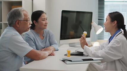 Asian female doctor explains how to take prescription medicine to elderly couple during a medical consultation in a modern clinic. Senior healthcare and patient care at hospital concept.