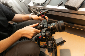 Manos de joven camarógrafa preparando cámaras y monitor en gimbal para registro audiovisual video	