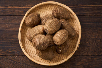 里芋（泥付き）を竹籠に盛った和風の食材カット