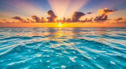 Vibrant sunrise over the ocean with sunbeams piercing through dramatic clouds above rippling water