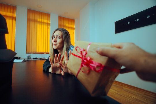 Woman Refusing a Gift She receives at Work from a Colleague. Unhappy office worker feeling unhappy about flirt or bribery attempt 
