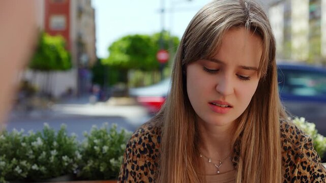 Multiple views of a 23 year old woman actively listening and responding during a conversation at an outdoor cafe, showcasing various facial expressions and reactions