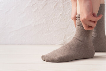A woman putting on socks.  靴下を履く女性