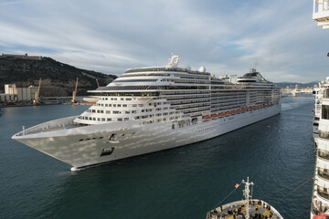 Massive Italian family cruiseship cruise ship Fantasia, Splendida or Divina in Barcelona, Spain during Summer Mediterranean cruising in sleek modern design with port infrasctructure and marine traffic