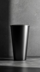 Black metal cup against a textured grey background in soft light