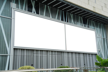 Mockups of two blank white billboards framed by a modern building facade, ideal for advertising