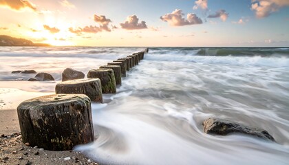 Ocean sunrise over weathered posts, silken waves gently wash shoreline