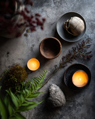 Minimalist Halloween flat lay featuring candles, skull, wooden bowls, stones, and greenery creates spooky yet serene atmosphere