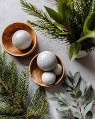 Minimalist holiday flat lay featuring ornaments, greenery, and wooden bowls, creating serene and festive atmosphere