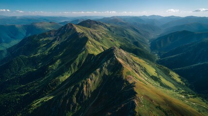 High angle aerial view captures vast expanse of rugged, verdant mountain ranges under clear sky