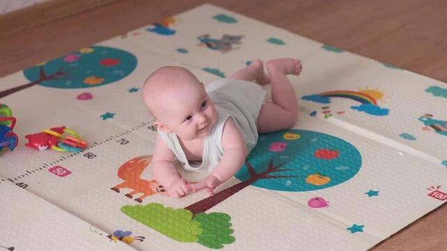 An adorable baby is crawling cheerfully on a vibrant and colorful playmat, exploring joyfully