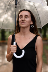 Woman umbrella rain standing peacefully outdoors enjoying a tranquil moment under a clear umbrella.