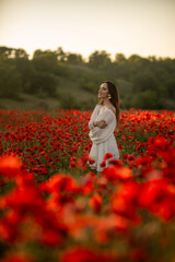Woman in white dress standing in poppy field.