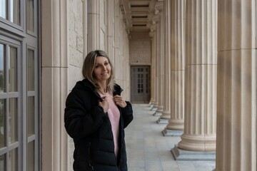Woman, columns, building. Smiling woman posing in a classic architectural colonnade with ample copy space