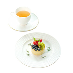 A delightful dessert of fruit tart alongside a cup of tea. A fresh cup of tea is accompanied by a beautifully crafted fruit tart on a elegant white plate.