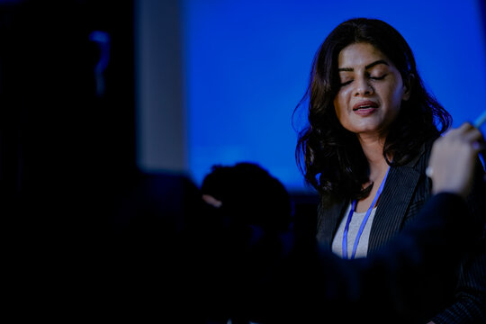 An Indian female software engineer or data scientist focuses during a technical briefing in a control room or at an AI developer conference. She is listening.