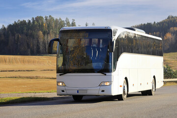 White Coach Bus on Road in Autumn. 