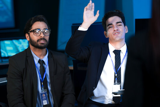 An Indian developer holds a tablet while a Caucasian engineer interacts with the screen. They are analyzing AI data or a cybersecurity system in a SOC. - Powered by Adobe
