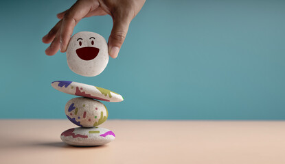 Enjoying Life Concept. Harmony and Positive Mind. Hand Setting Smiling Pebble Stone Stack
