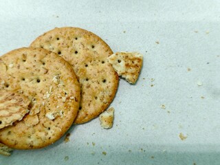 Broken Whole Wheat Crackers with Crumbs on White Paper Background, Top View