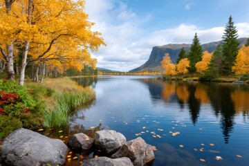 Fototapeta premium Autumn leaves floating on a serene lake reflecting mountains