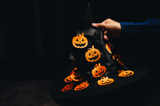 Halloween witch hat decorated with playful orange pumpkins and dark background, perfect for festive celebrations and themed events - Powered by Adobe