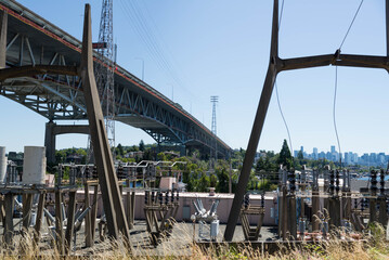Low angle view of freeway bridge, specifically the the Ship Canal Bridge/I-5, as seen from behind transformer station. Taken while walking in the Seattle urban area on a clear July day.