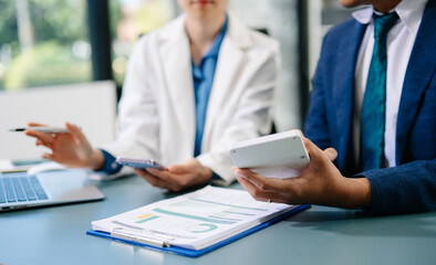 Professional businesspeople analyzing data, discussing strategy, and collaborating on financial reports in a modern corporate office setting.