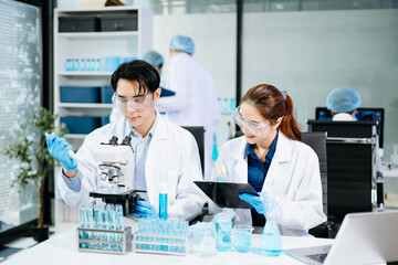 Team of scientists analyzing blue liquid samples in a modern lab, showcasing biotechnology, chemistry, and medical research innovation.