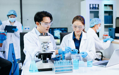 Fototapeta premium Team of scientists analyzing blue liquid samples in a modern lab, showcasing biotechnology, chemistry, and medical research innovation.