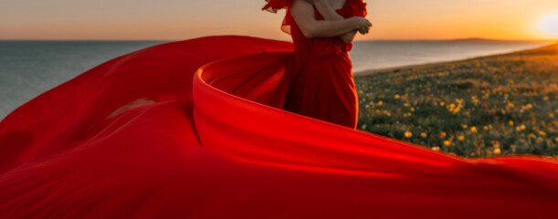 Red dress photoshoot sunrise beach field, woman posing for artistic photos due to beautiful scenery.