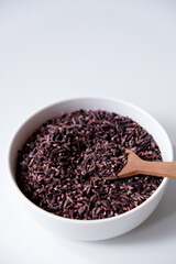 A bowl of black sticky rice grains isolated on white background