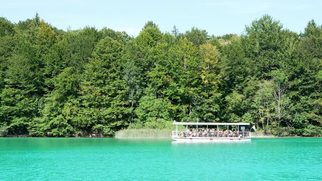 Tourist boat sailing on turquoise lake in Plitvice Lakes National Park, Croatia