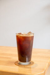 A glass of iced americano on the wooden table in a cafe