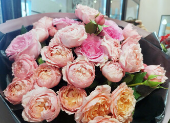 Stunning bouquet of light pink and peach roses, beautifully wrapped in dark and light paper. A perfect gift for any special occasion
