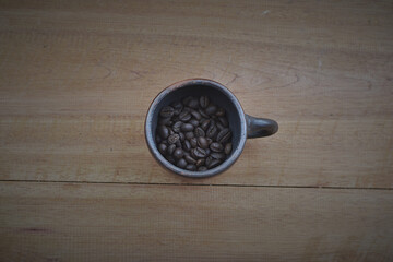 Coffee beans with a clay cup on a wooden table