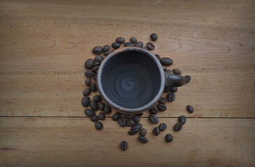 Coffee beans with a clay cup on a wooden table
